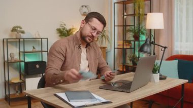 Planlama bütçesi. Zengin mutlu işadamı Ukrayna 'nın Hryvnias UAH nakitini hesaplamak için evde dizüstü bilgisayar kullanıyor. Planlanan tatil hediyeleri için maaş kazancından memnun olan adam..