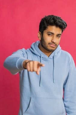 Seni seçiyorum. Hintli gülümseyen adam kamerayı işaret ediyor ve neşeli bir ifadeyle bakıyor, kazanan seçimi yapıyor, yön gösteriyor. Kırmızı stüdyo arka planında izole Arap genç adam
