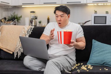 Evdeki Asyalı adam dizüstü bilgisayardaki korkunç gerilim filmlerini izliyor. Korkutucu bir şekilde sıçrıyor, patlamış mısır döküyor, sonra nefes alıyor ve nabzı yavaşlıyor. Kanepede oturan Çinli adam meraklı bir şekilde bakkala sıkıca sarılıp bükülmeyi bekliyor.