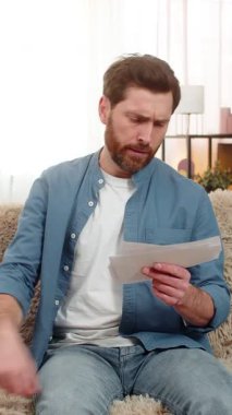 Evdeki kızgın genç adam çaresizce ödenmemiş faturaları kanepeye atıyor, bunalmış hissediyor. Kafkasyalı adam hayal kırıklığıyla kafasını sıkıyor, mali borçlarla boğuşuyor ve harcamaları artıyor.