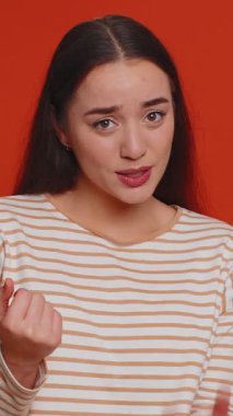 Biraz daha, lütfen bana ver. Hoş bir kadın şüpheci bir gülümsemeyle küçük boyutlarda, minimum işaret gösteren küçük bir jest yapıyor. Kırmızı stüdyo arka planında yalnız yaşayan genç bir kız.