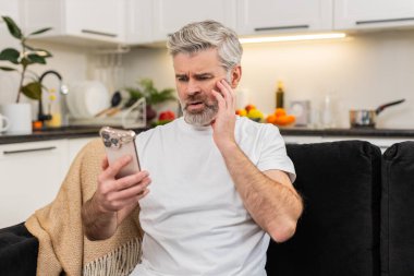 Evde akıllı telefondan konuşan orta yaşlı bir adam başarısız bir oyun oyunu ya da iş inkar haberlerini izler ve kafasını sallar. Kanepede oturan olgun bir adam gözlerini indirir derin derin nefes alır ve duyguları sakinleştirmeye çalışır ve sonucu kabullenmeye çalışır.