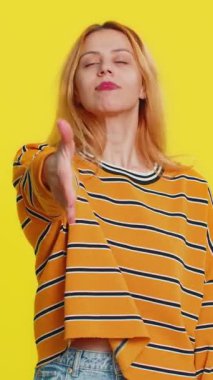 Dost canlısı beyaz kadın bluz giymiş kameraya uzanan, el sıkışma teklif eden nazik bir gülümseme, davetiye, dayanışma gösteren bir karşılama sarı arka planda güven kavramı.