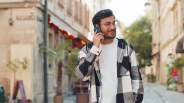 Hintli genç turist arkadaşlarıyla uzaktan iletişim kuruyor, cep telefonuyla konuşuyor şehir caddesinde beklenmedik iyi haber dedikoduları yapıyor. Kasaba yaşam tarzları.