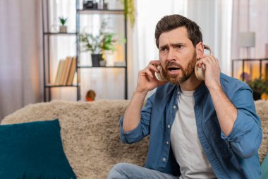 Evde kulaklık takan bir adam garip bir ses duyduktan sonra şaşırmış bir şekilde aniden çıkartıyor. Kanepede oturan beyaz adam gürültüyü tespit etmeye çalışırken merak ve endişeyle tepki veriyor.