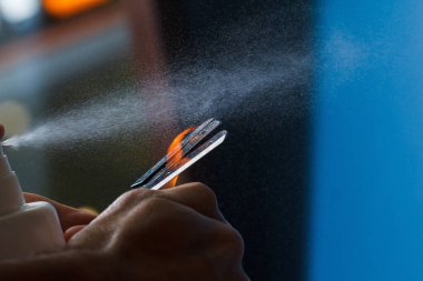 Kullanmadan önce tıraş aletini dezenfekte etmek. Genç adam jilete antibakteriyel sıvı püskürtüyor..