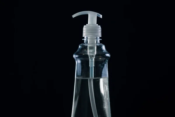 プラスチックボトルに隔離されたアルコールハンド消毒剤、黒の背景に撮影スタジオ. — ストック写真