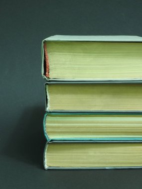 Koyu arkaplanda sarı bomaga olan eski renkli kitaplar.