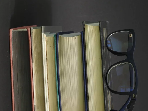 Oude Boeken Met Gekleurde Omslagen Gele Lakens Leesbril Donkere Achtergrond — Stockfoto