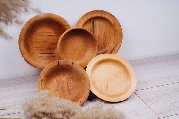 A set of plates made of recycled material. Natural wood utensils. Zero waste. Reusable utensils. Reeds adorn the composition with wooden dishes.