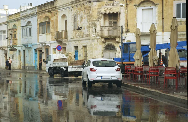 MARSAXLOKK, MALTA-dec 18: rua na típica aldeia maltesa colorida Marsaxlokk em 18 de dezembro de 2015 em dia nublado chuvoso. Vida típica diária em pequena aldeia de Marsaxlokk. Malta. Chuveiros em Malta Island, Malta — Fotografia de Stock