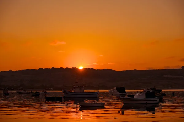 Laranja dramática nascer do sol com os barcos de pesca no fundo em Marsaxlokk, Malta. Destino de viagem em Malta — Fotografia de Stock