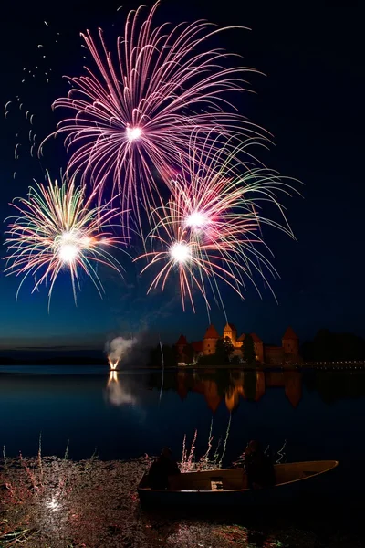 Stora färgglada fyrverkerier exploderar med fin reflektion på ett vatten, juli, oberoende, fyrverkerier med gamla slottet i bakgrunden — Stockfoto