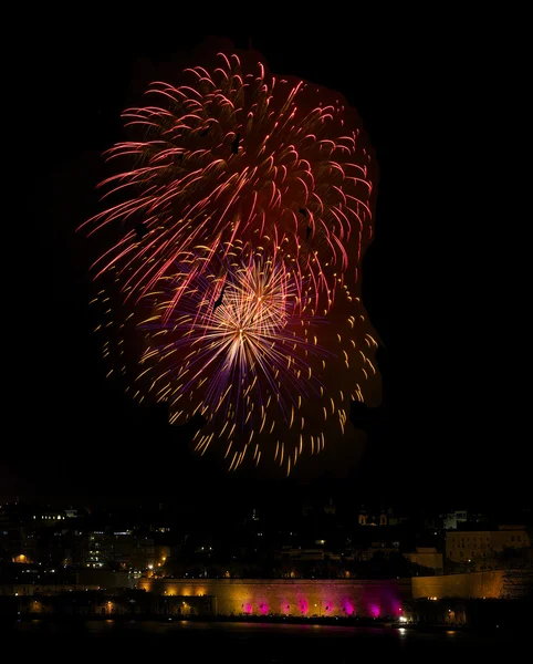 Fireworks.Colourful fireworks in Malta with dark sky and house light background,Malta fireworks festival, Independence day,New Year, fireworks explosion with reflection on sea, fireworks in Valletta — Stock Photo, Image