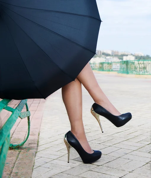 Красиві жіночі ноги з чорним взуттям на вулиці, жіночі ноги з взуттям на високих підборах на природному темному тлі вулиці, жіночі ноги, фрагмент жіночого тіла — стокове фото