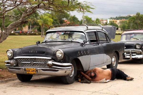 GUARDALAVACA, CUBA - 18 de junio: hombre reparando un viejo auto cubano en la típica y colorida calle cubana el 18 de junio de 2006. La vida cotidiana del pueblo cubano. Cuestión social de Cuba — Foto de Stock