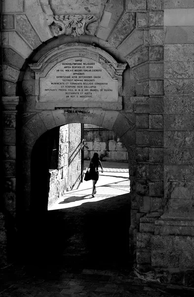 Donna single che va in arco in ombra a Birgu, Malta, Europa, solitudine, donna che va, foto in bianco e nero contrasto, umore solitudine, solitudine, strada a Malta — Foto Stock