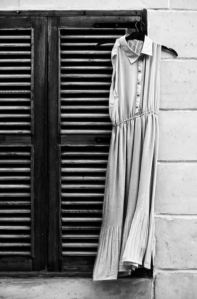 Старое платье на окне в черно-белом фото, концептуальное фото старого платья, винтажное фото, винтажное платье потеряно на улице — стоковое фото