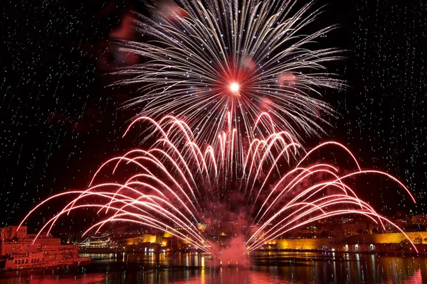 Coloridos fuegos artificiales explotan en Malta en el cielo oscuro, Malta festival de fuegos artificiales, 4 Julio, Día de la Independencia, fuegos artificiales explotan, Año Nuevo, fuegos artificiales en La Valeta aislados en el fondo oscuro con lugar para el texto —  Fotos de Stock