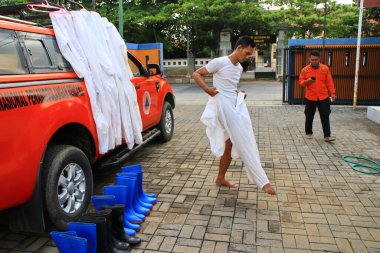 Kamu mezarlığı Pekalongan 'da, 3 Kasım 2020' de kişisel koruma ekipmanlarıyla memurlar tarafından katı sağlık protokolleri uygulanmış 19 hasta için cenaze töreni.