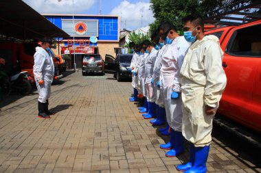 Kamu mezarlığı Pekalongan 'da, 3 Kasım 2020' de kişisel koruma ekipmanlarıyla memurlar tarafından katı sağlık protokolleri uygulanmış 19 hasta için cenaze töreni.