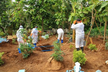 Kamu mezarlığı Pekalongan 'da, 3 Kasım 2020' de kişisel koruma ekipmanlarıyla memurlar tarafından katı sağlık protokolleri uygulanmış 19 hasta için cenaze töreni.