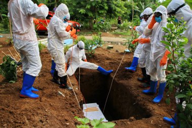 Kamu mezarlığı Pekalongan 'da, 3 Kasım 2020' de kişisel koruma ekipmanlarıyla memurlar tarafından katı sağlık protokolleri uygulanmış 19 hasta için cenaze töreni.