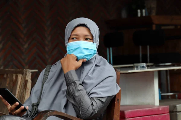 Beautiful women wearing hijab and mask, while relaxing in a cool cafe, Selective focus  and noise image