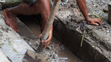 Seçici odak resmi, tıkanmış çöplerden kanalizasyon temizleyen işçiler