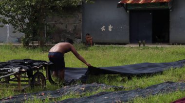 Sıcak bir günde, Pekalongan, Endonezya, 8 Mart 2021 'de tarlada batik kumaş kurutan işçiler.