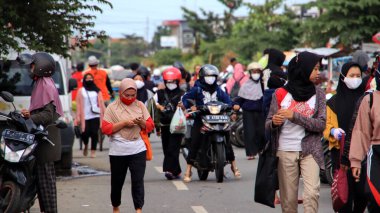 Fabrika işçileri işten eve gelir, 22 Şubat 2021 'de Pekalongan caddesindeki motosikletlerine yürürler.