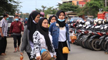 Fabrika işçileri işten eve gelir, 22 Şubat 2021 'de Pekalongan caddesindeki motosikletlerine yürürler.