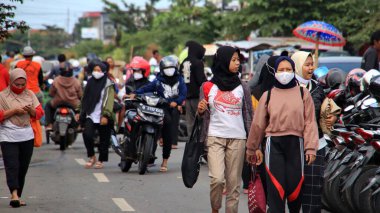 Fabrika işçileri işten eve gelir, 22 Şubat 2021 'de Pekalongan caddesindeki motosikletlerine yürürler.