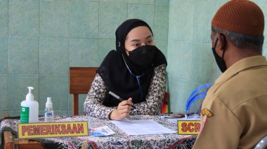 Doktorun elinde şırınga tutması ve pamuk kullanması tıbbi maske Covid-19 veya koronavirüs aşısı, Batang, Endonezya, 15 Mart 2021