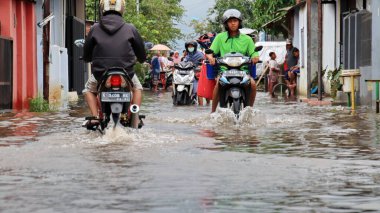 Blurry image by several motorbike riders and cars passing the flood, Pekalongan,  February 18, 2021 clipart