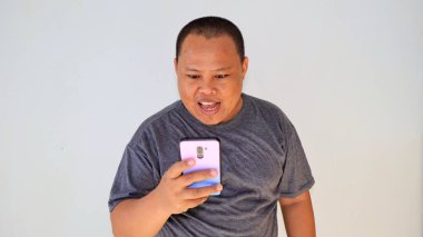 Akıllı telefonuyla oyunu kaybettikten sonra, stresli bir ifadeyle duygusal hisseden bir adam.