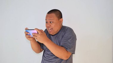 Akıllı telefonuyla oyunu kaybettikten sonra, stresli bir ifadeyle duygusal hisseden bir adam.