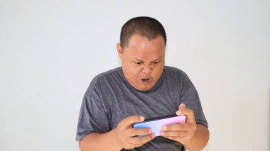 Akıllı telefonuyla oyunu kaybettikten sonra, stresli bir ifadeyle duygusal hisseden bir adam.