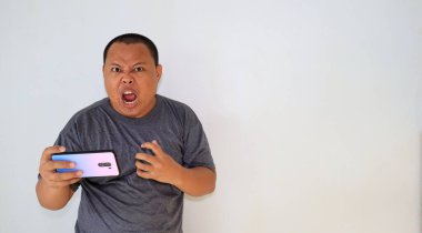 Akıllı telefonuyla oyunu kaybettikten sonra, stresli bir ifadeyle duygusal hisseden bir adam.