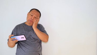 Akıllı telefonuyla oyunu kaybettikten sonra, stresli bir ifadeyle duygusal hisseden bir adam.