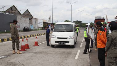 Endonezya Ulusal Polisi ve Silahlı Kuvvetler 'in güvenlik görevlileri, 17 Haziran 2021' de Covid 19, Pekalongan 'ın transmisyonu için kontrol edilmek üzere Toll Road' dan ayrılan araçları durdurdular.