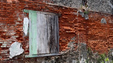 Eski tuğla duvar yaş ve havan ve solmuş kırmızı tuğlalarla yıpranma belirtileri gösteriyor, desenli ve kırsal bir zemin oluşturuyor.