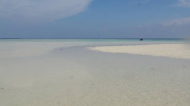 Turkuaz su, tropikal sahillerin huzur veren güzelliğini gösteren parlak bir kumsalda nazikçe tur atar..