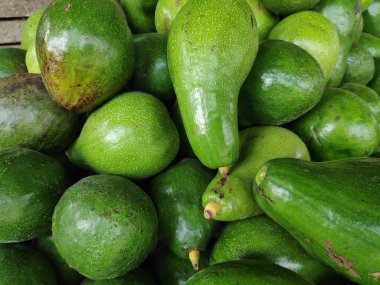 Açık hava pazarında sergilenen olgun avokado yığınları canlı yeşil derilerini ve pürüzsüz dokularını sergiliyor, sağlıklı beslenmeyi ve aşçılık yaratıcılığını teşvik ediyor..