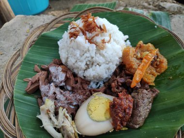 Geleneksel bir java yemeği olan Nasi Gudeg, muz yaprağında pilav, tavuk, yumurta ve meyveli, Endonezya mutfağı sergileniyor..