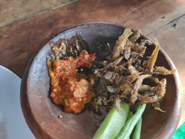 Geleneksel Endonezya yemeği: Kızarmış ançüez, baharatlı sambal ve taze sebzeler otantik yemek pişirme deneyimi için kırsal kilden servis edilir..