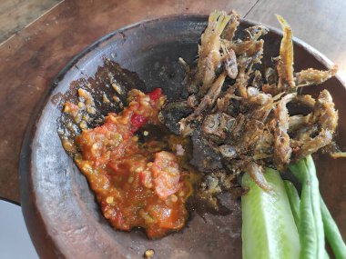 Geleneksel Endonezya yemeği: Kızarmış ançüez, baharatlı sambal ve taze sebzeler otantik yemek pişirme deneyimi için kırsal kilden servis edilir..