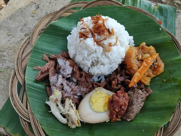 Geleneksel bir java yemeği olan Nasi Gudeg, muz yaprağında pilav, tavuk, yumurta ve meyveli, Endonezya mutfağı sergileniyor..