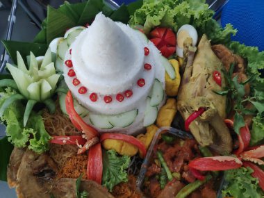 Geleneksel Endonezya yemeği olan Nasi tumpeng, koni şeklinde bir pirinç tabağıdır ve genellikle sarıdır. Çeşitli mezeler ve sebzelerle servis edilir, muz yapraklarıyla kaplı bir sepette daire şeklinde düzenlenir..