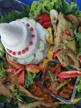 Geleneksel bir Endonezya yemeği olan Tumpeng pilavı, çeşitli mezeler ve sebzelerle servis edilen koni şeklinde pirinç olup, tampon astarlı bir daire şeklinde dizilmiştir..